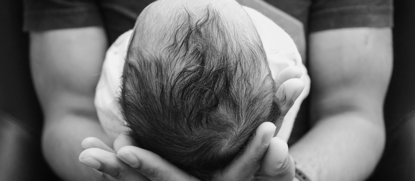 A newborn cradled in a parent's hands